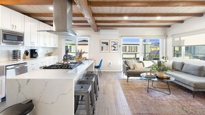 Une cuisine moderne avec des meubles blancs, un four à micro-ondes en acier inoxydable et un grand îlot central doté de tabourets.