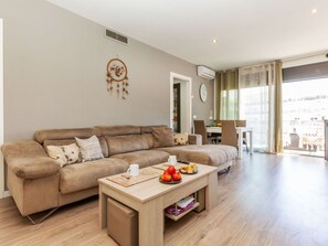 A living room with a sofa, a coffee table, and a dining area in the background.