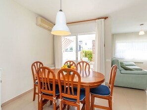 A dining area with a round wooden table and chairs, a hanging pendant light, and a view of the outside balcony. - Beautiful  villa for 6 guests with private pool, A/C, WIFI, TV and terrace (Torredembarra)