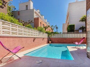 A swimming pool with two pink lounge chairs, a white decorative fence, and buildings in the background. - Beautiful  villa for 6 guests with private pool, A/C, WIFI, TV and terrace (Torredembarra)