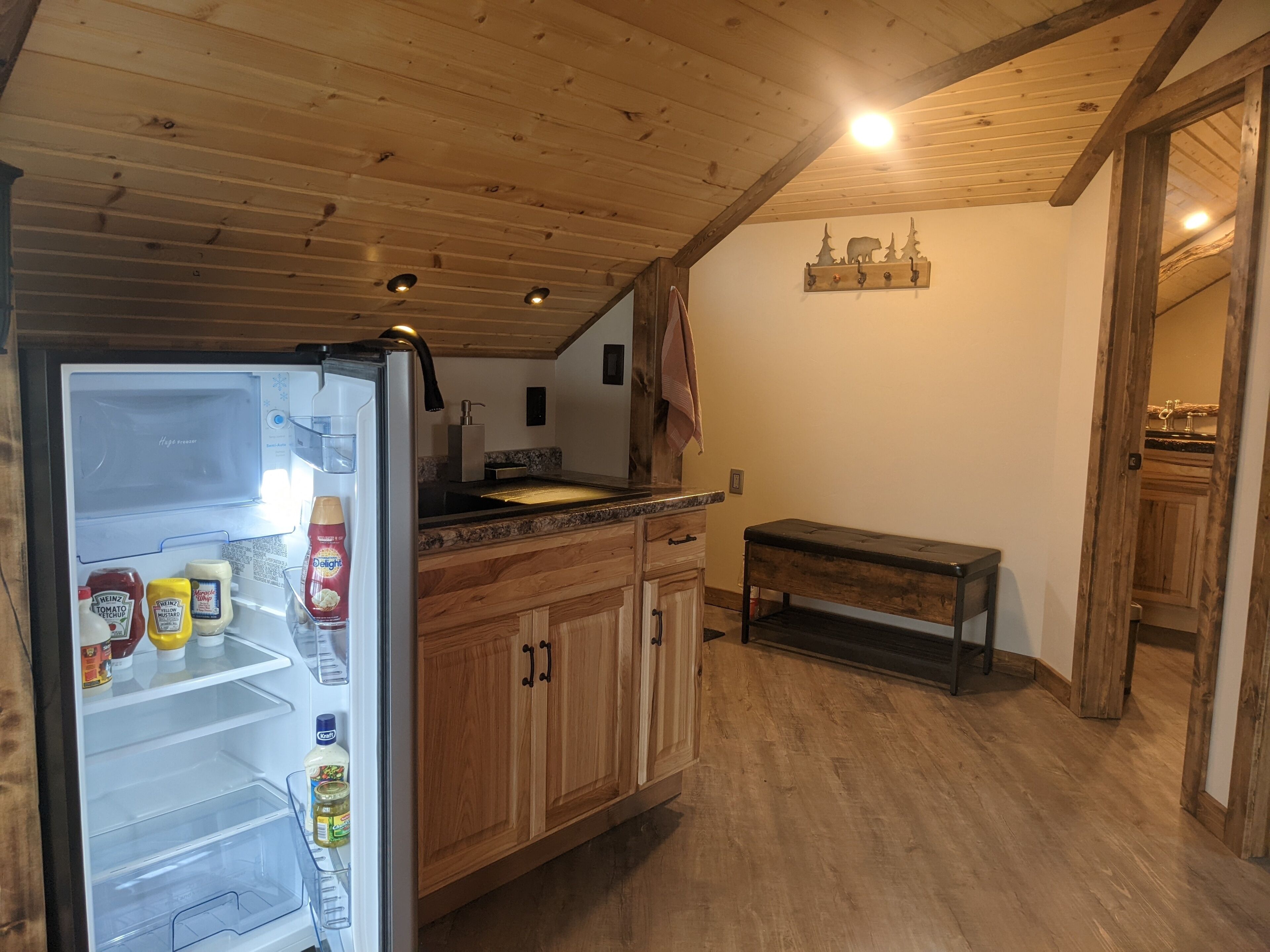 Eine Küche mit Holzausstattung, einer integrierten Sitzbank und einem mit Gewürzen gefüllten Kühlschrank.