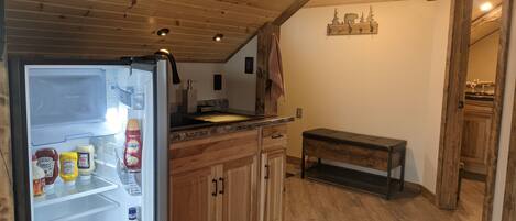 A kitchen with wooden cabinets, a built-in bench, and a refrigerator stocked with condiments.