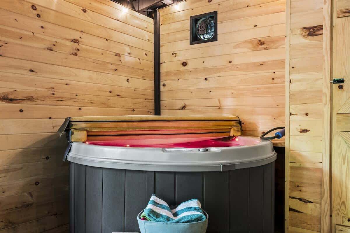 A wooden cabin with a hot tub and a small window.