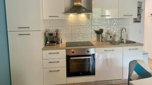 Een moderne keuken met witte kasten, een inbouwoven, een koffiezetapparaat en een roestvrijstalen afzuigkap.