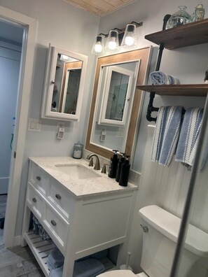 A bathroom with two sinks, a toilet, a mirror, and a shelf with towels. - VITAMEN SEA AND OCEAN WAVES 3 BDRM RETREAT (Indian Shores)