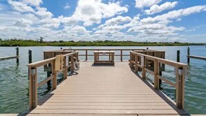 Une jetée en bois s’étendant sur une étendue d’eau calme, sous un ciel dégagé.