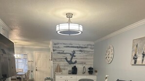 Un salon avec un canapé gris foncé, une table basse en bois, un meuble blanc et une horloge murale.
