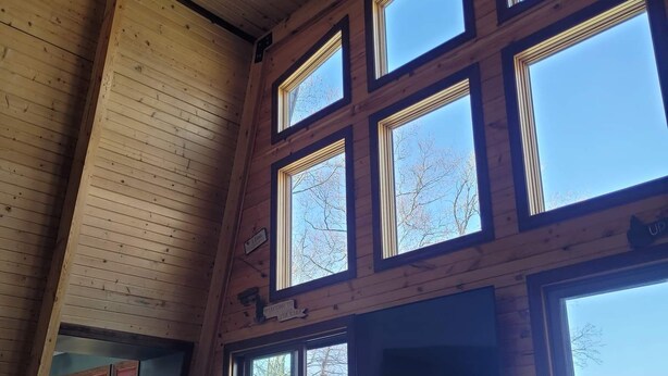A spacious room with high ceilings and large windows, offering views of a lake.