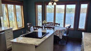 A kitchen with a central island, wooden flooring, and large windows overlooking a lake.