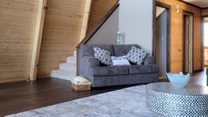 A modern living room with a grey sofa, patterned rug, and a unique light bowl on a round table.