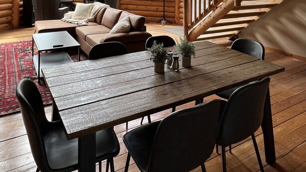 A spacious log cabin interior with a large dining table, a sofa, and a staircase. - Cozy Log Cabin Near Indiana Dunes & Lake Michigan! (Portage)