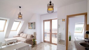 A modern, well-lit living room with a sofa, a dining table, and a kitchen area with a sink. - Brand New Apartment with pool, gym and playground (Kamchia)