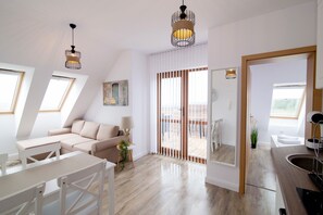 Una sala de estar moderna y bien iluminada con un sofá, una mesa de comedor y una zona de cocina con un fregadero.