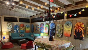 A cozy room with a wooden ceiling, colorful wall art, a teal sofa, and a dining table with chairs. - Fun w/Loft! Beach ~Nature Trails ~Grill~ Firepit ~Indiana Dunes National Park  (Gary)