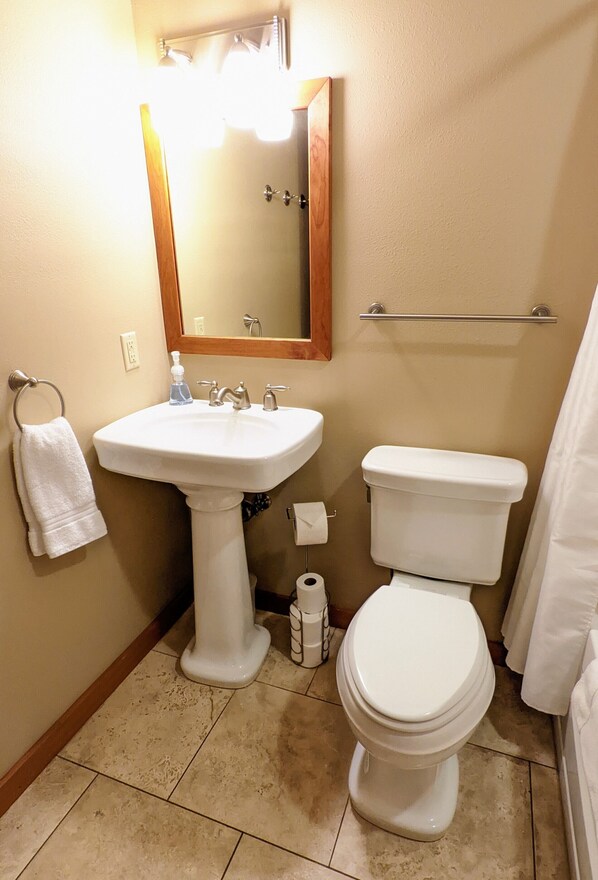A bathroom with a white sink, a toilet, a mirror, and a towel rack.
