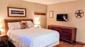 A neatly arranged bedroom with a large bed, a wooden dresser, a television, and a framed picture on the wall. - Starboard Cabana - Unit 2 (Chelan)