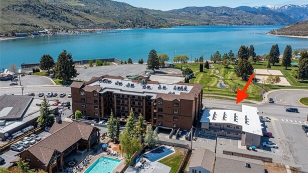 A hotel with a swimming pool, a parking lot, and a view of a lake and mountains. - Starboard Cabana - Unit 2 (Chelan)