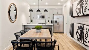 Cocina moderna con armarios blancos, una isla central, microondas, refrigerador e iluminación colgante.