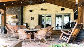 An outdoor patio with wicker furniture, a grill, and a stone wall. - Amazing lakefront home with custom boat dock! (Quinlan)