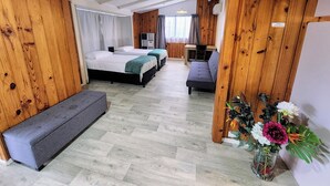 Una habitación con dos camas, un banco, un escritorio y un arreglo floral.
