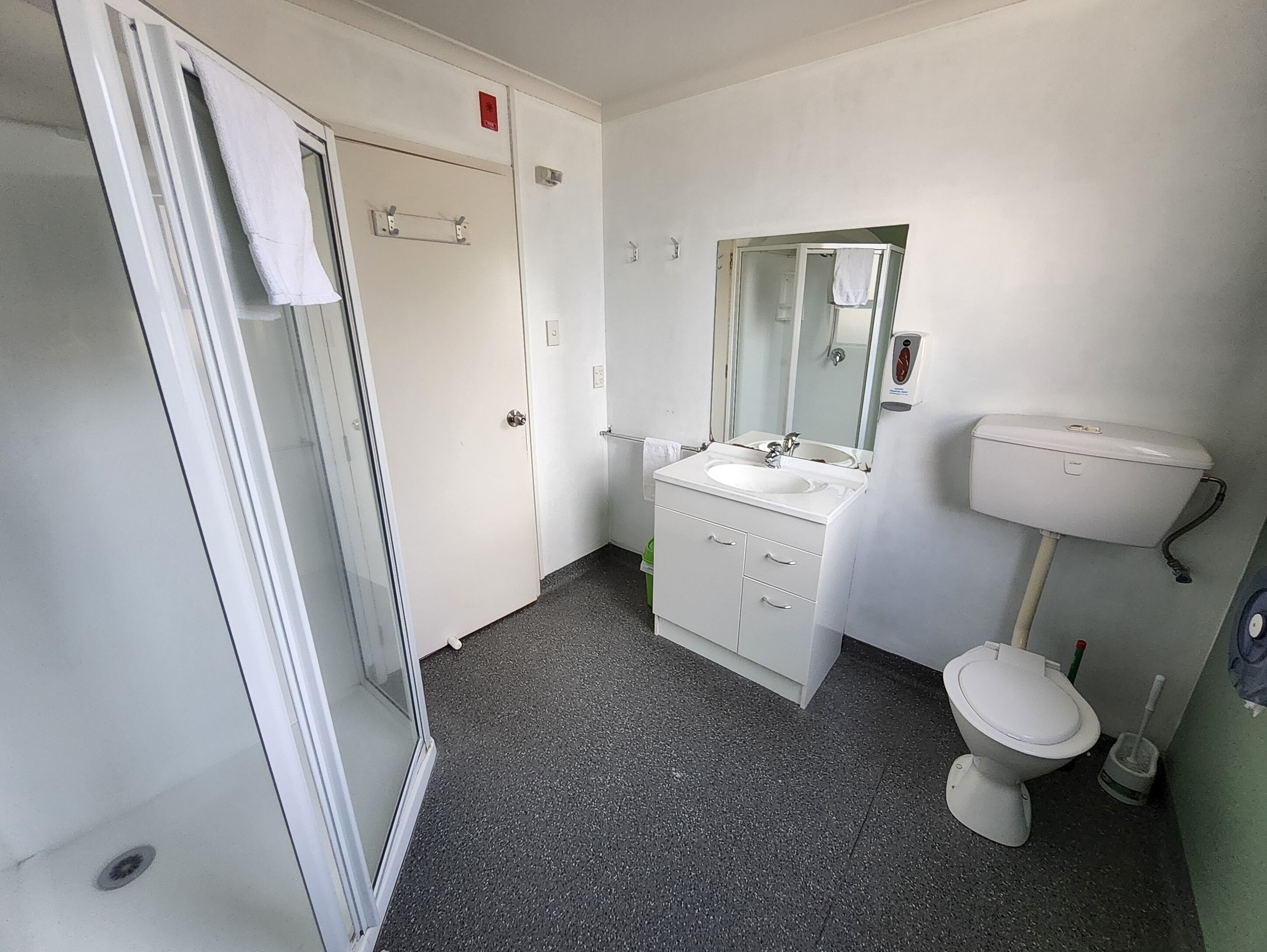 A bathroom with a shower, sink, toilet, and a mirror.