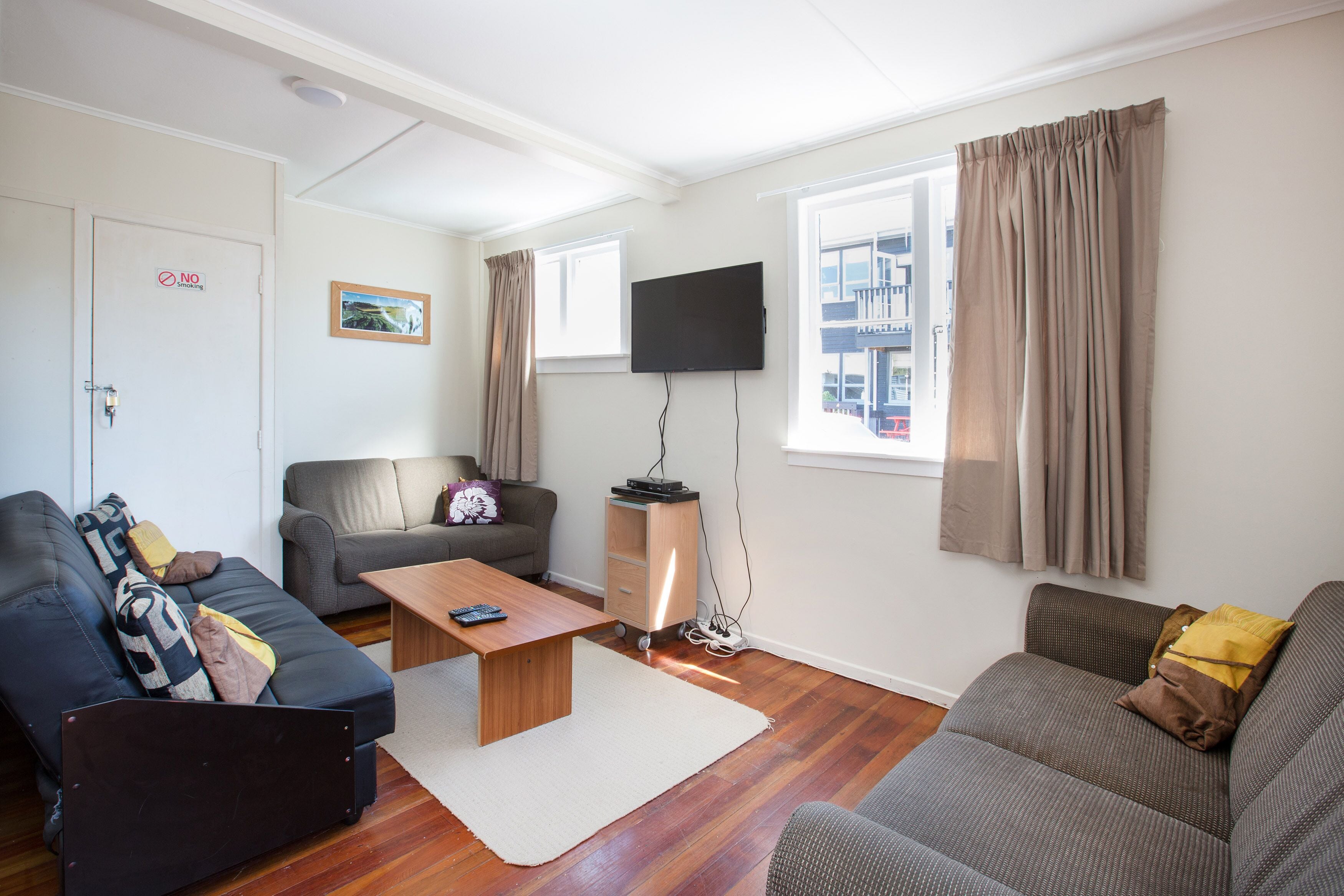 A modern living room with a sofa, a coffee table, a TV, and a window with curtains.