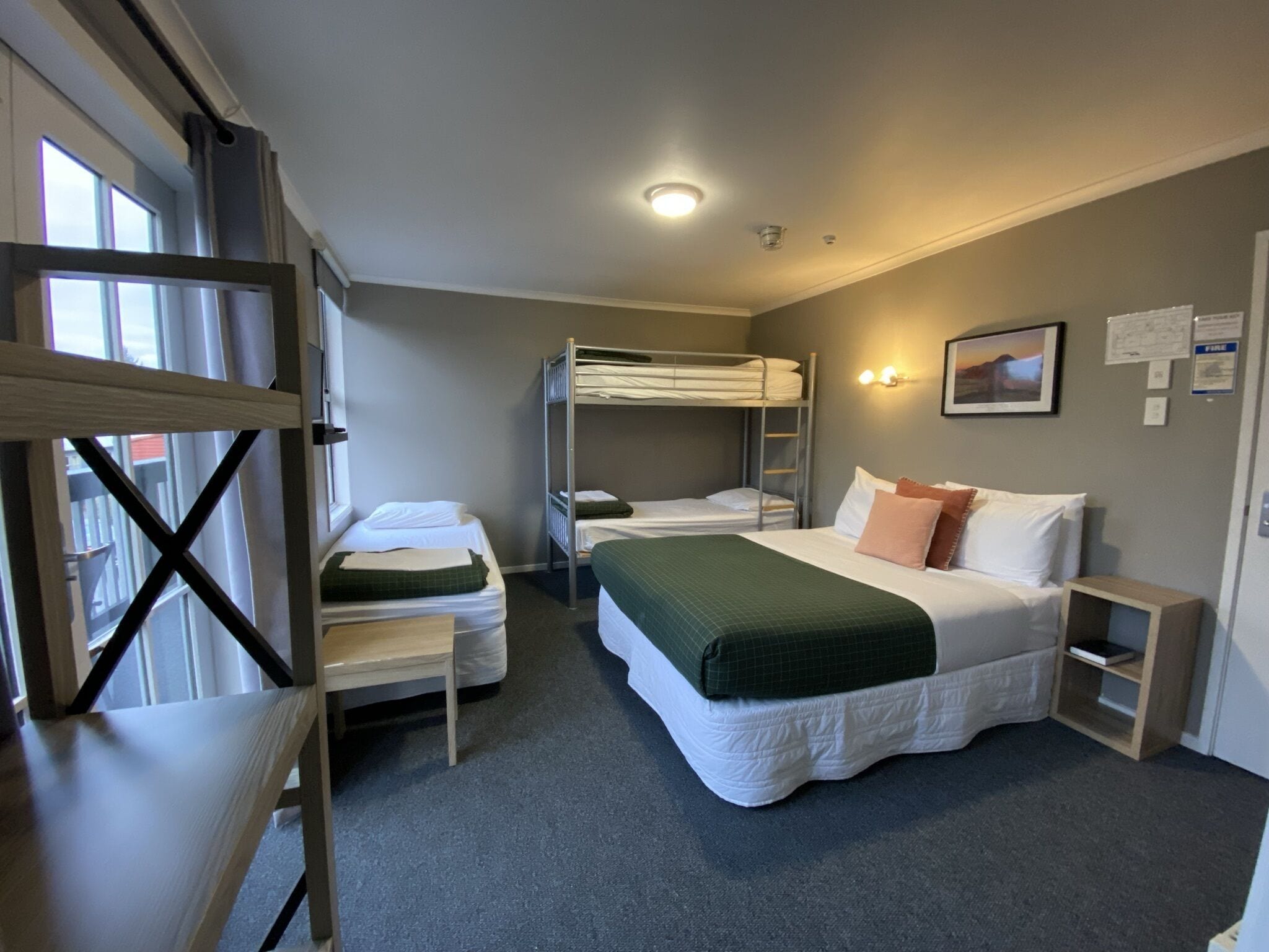 Ein Zimmer mit Etagenbetten, einem Einzelbett, einem Schreibtisch und einem Stuhl.
