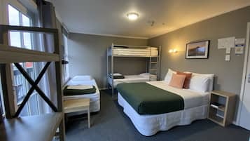 Ein Zimmer mit Etagenbetten, einem Einzelbett, einem Schreibtisch und einem Stuhl.