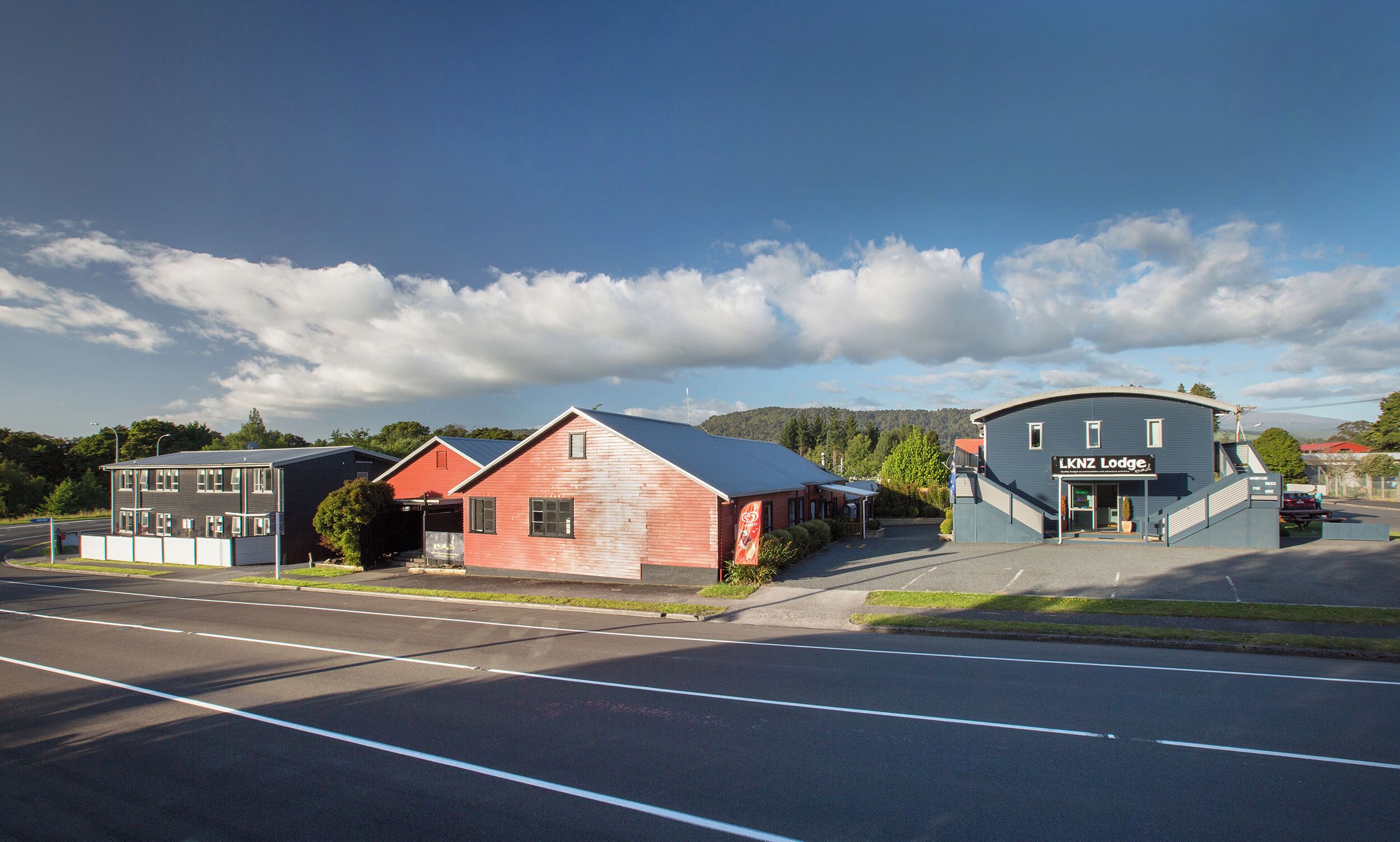 A building with a sign reading "LKNZ Lodge" and a parking lot in front.