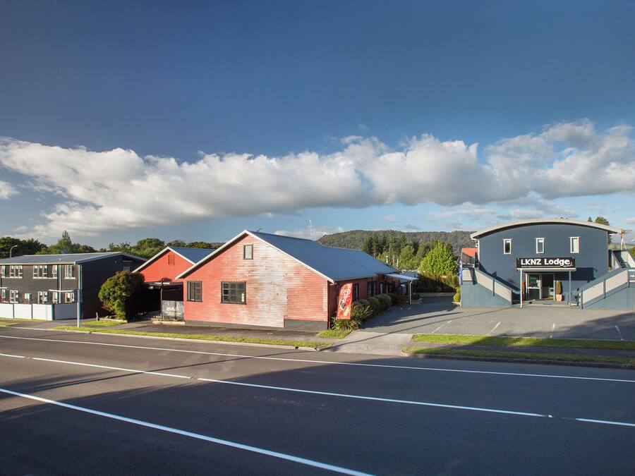 A building with a sign reading "LKNZ Lodge" and a parking lot in front.