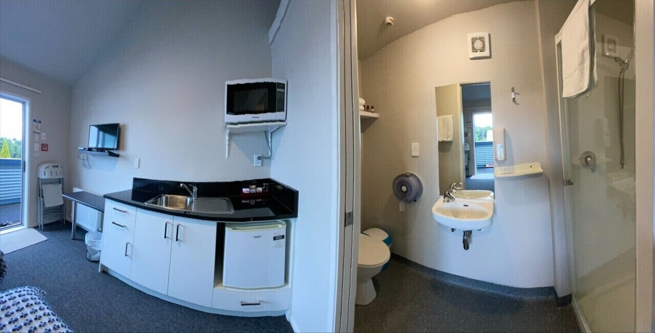 A compact bathroom with a toilet, sink, and a microwave above the counter.