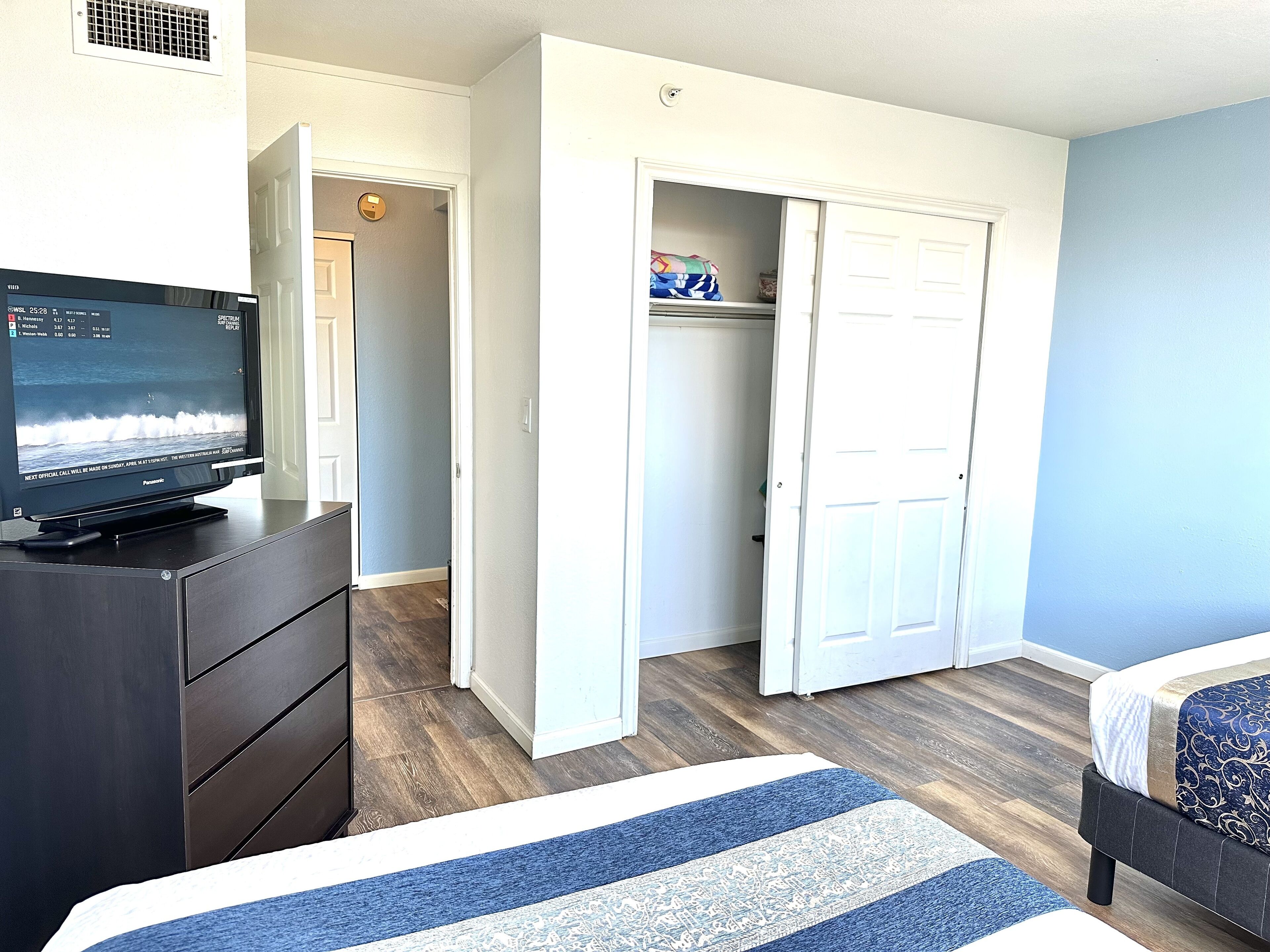 A bedroom with a bed, a dresser, a television, and a closet.