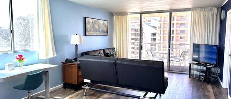 A modern hotel room with a bed, desk, chair, and a TV.