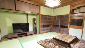 Una tradizionale stanza giapponese con pavimento in tatami, televisore, porte scorrevoli e un tavolino in legno.