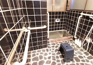 A bathroom with black tiled walls, a white bathtub, and a shower area. - Villa EL 5 (Nikko)