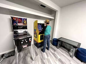 A room with a gaming console featuring Marvel characters, a small table, and a bench.