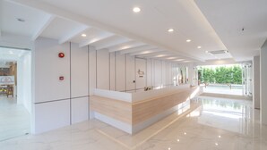 Een moderne receptie met een houten receptiebalie, witte wanden en een marmeren vloer.