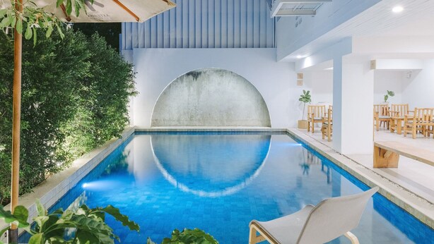 Een binnenzwembad met een helderblauw wateroppervlak, omringd door groen en moderne architectuur.