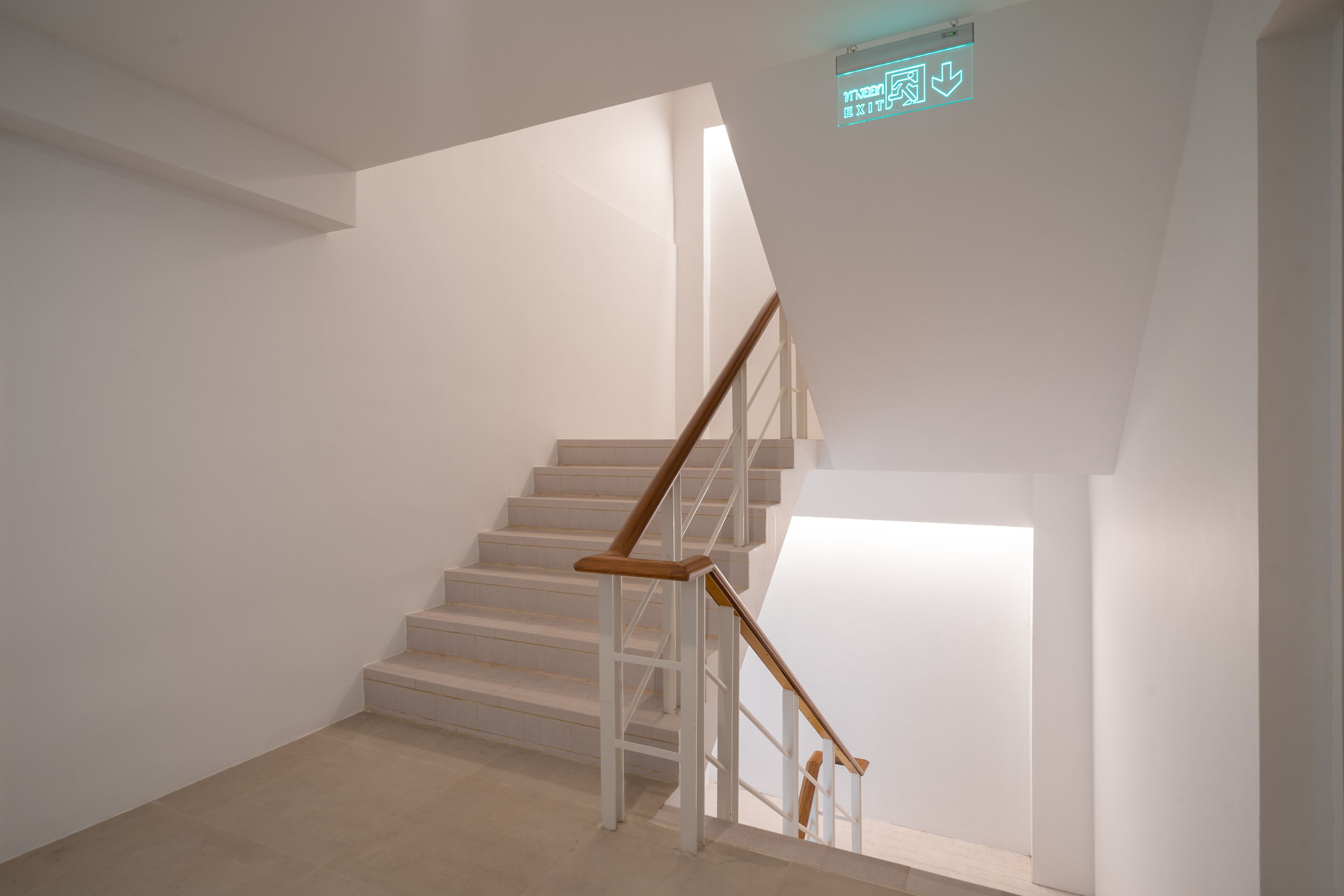 Una escalera con paredes blancas y barandilla de madera.