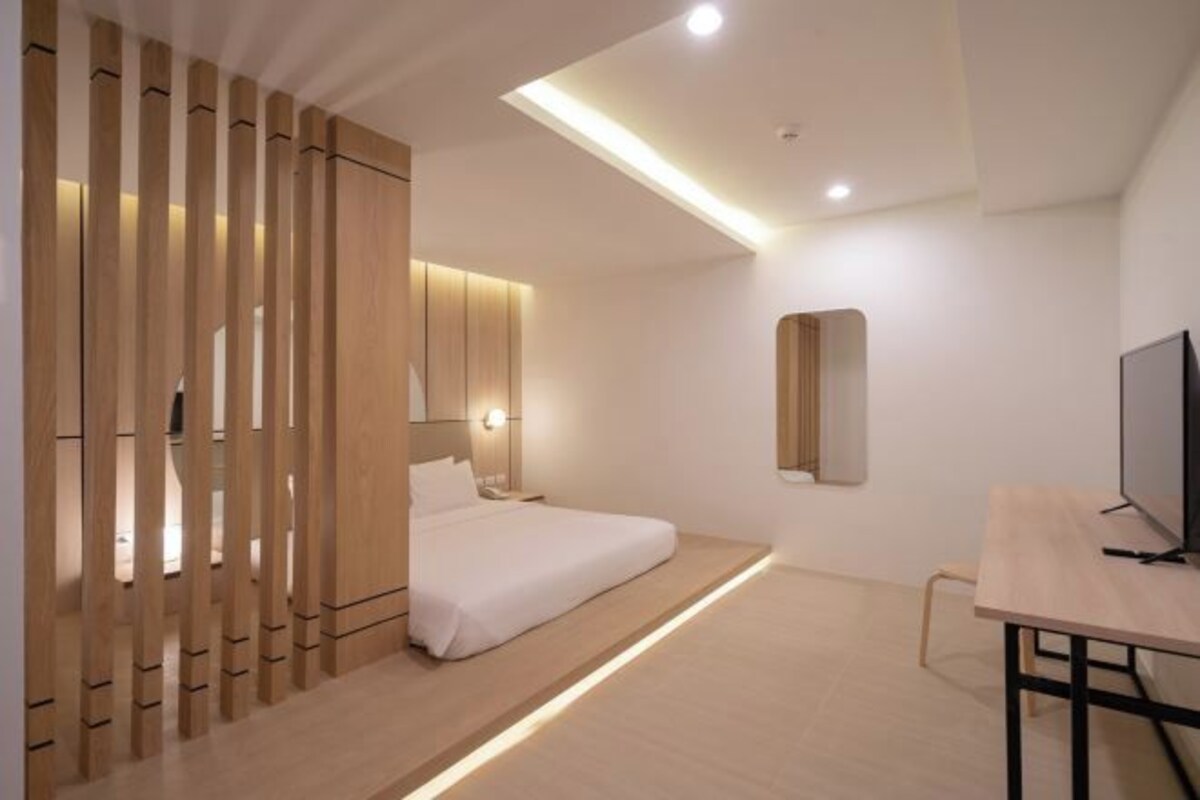 A modern hotel room with a bed, bedside table, and a TV.