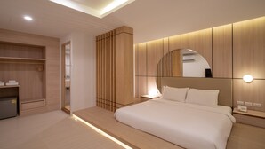 Een moderne hotelkamer met een groot bed, een inbouwkast en een nachtkastje met een lamp.