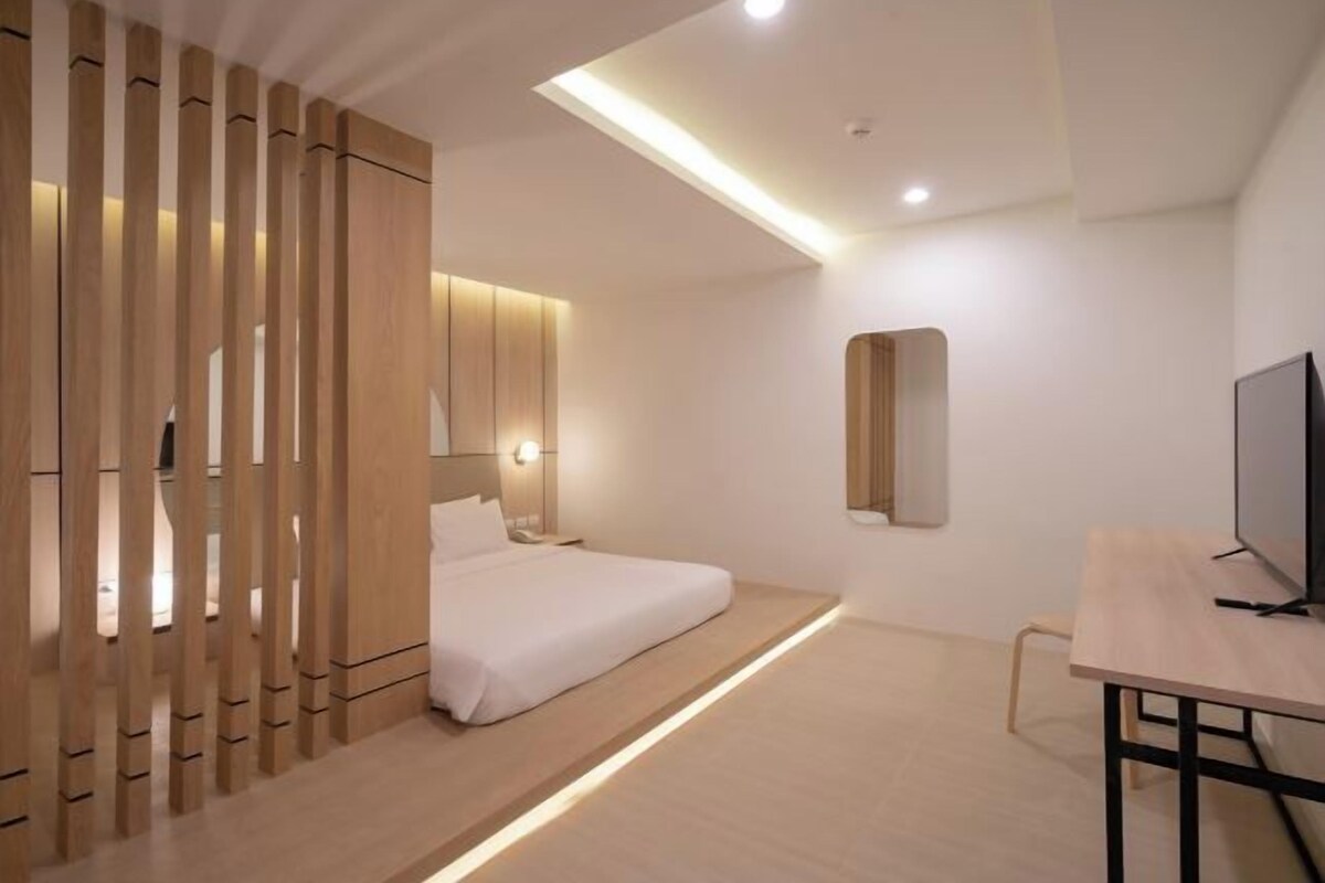 A modern hotel room with a bed, bedside table, and a TV.