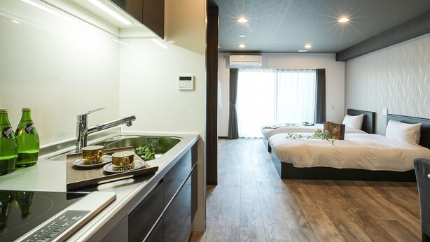 A modern hotel room with a kitchen area, a bed with a large window, and a built-in air conditioning unit. - Vacation Rent Kanazawa (Kanazawa)