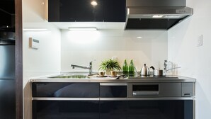 A modern kitchen with a stainless steel countertop, a built-in oven, and a black range hood. - Vacation Rent Kanazawa (Kanazawa)