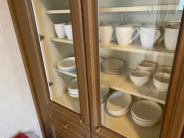 Un meuble avec plusieurs étagères contenant de la vaisselle et des bols en céramique blanche.