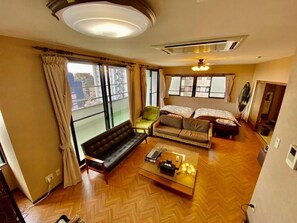 Ein geräumiges Wohnzimmer mit einer Couch, einem Couchtisch und Blick auf die Stadt durch große Fenster.