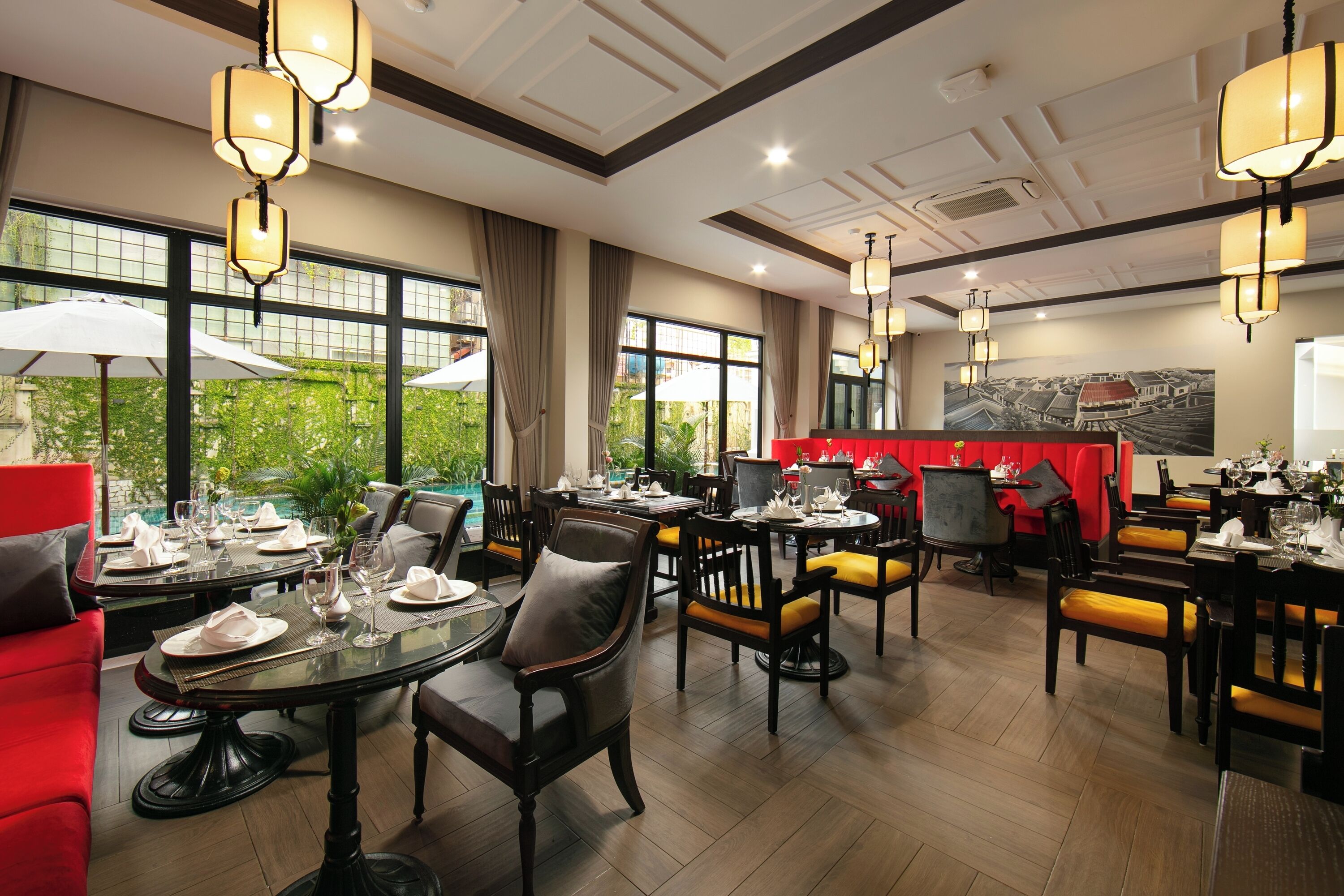 A restaurant with tables set for dining, chairs, and hanging lamps.