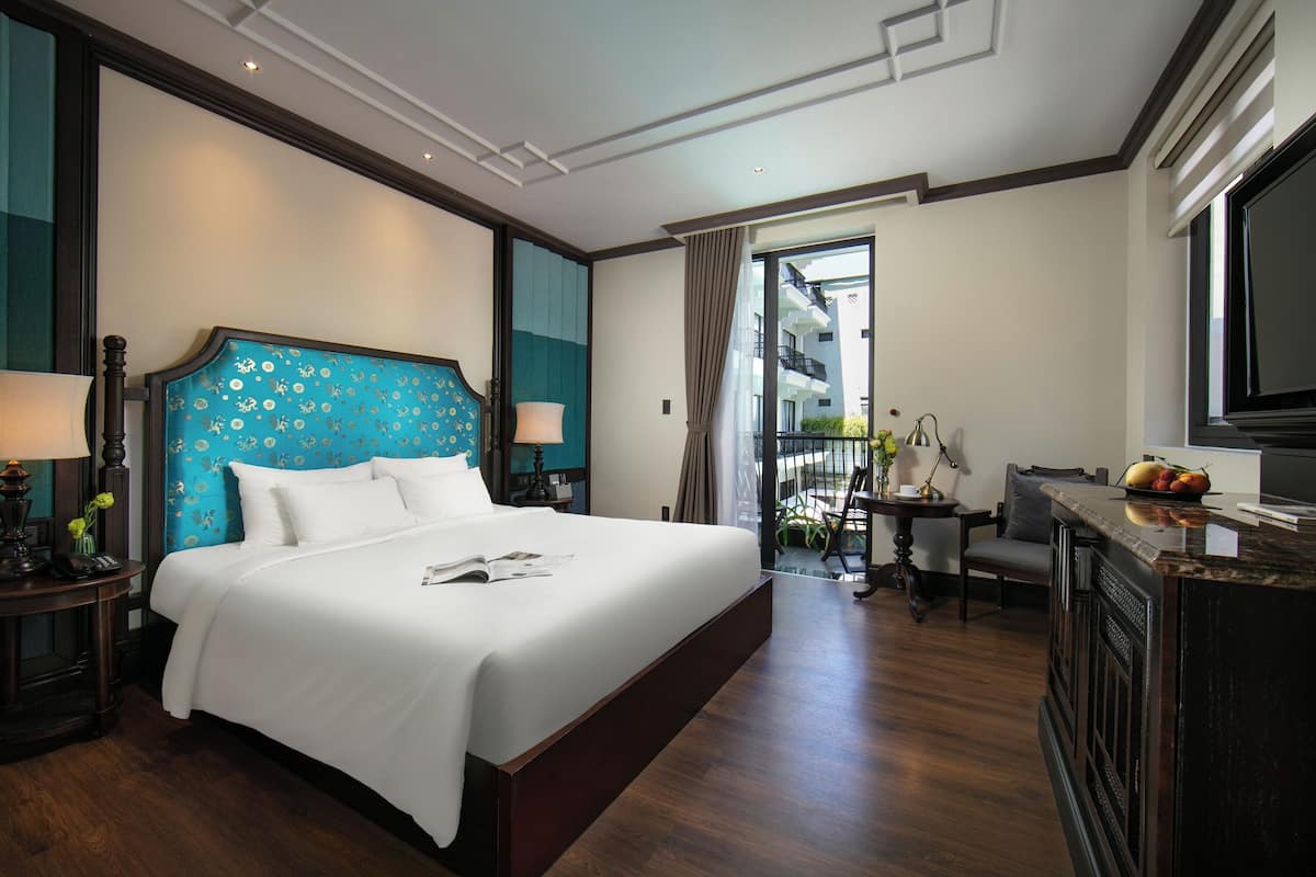 Ein Hotelzimmer mit einem großen Bett, einem Schreibtisch und Blick auf den Balkon.