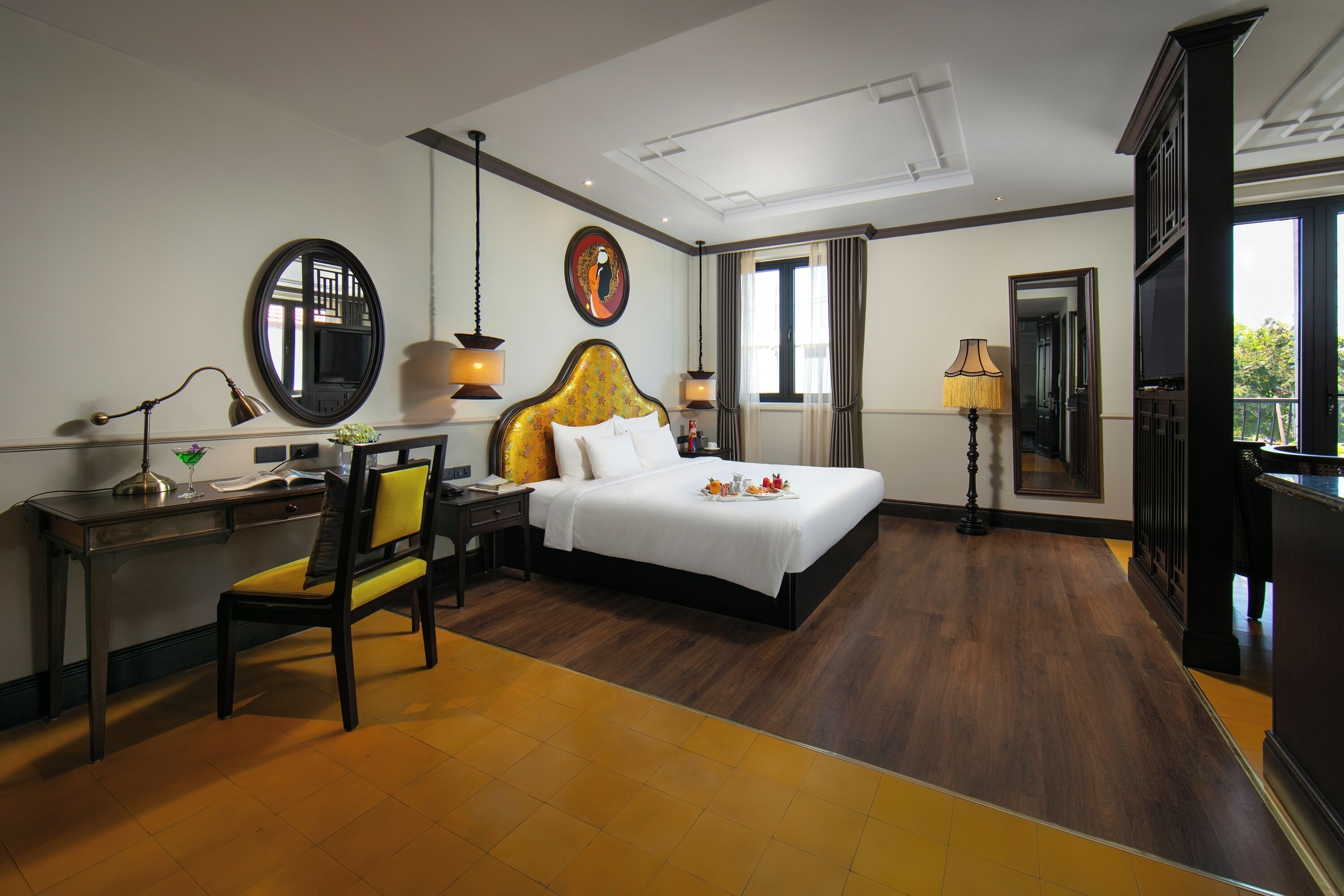 A hotel room with a bed, desk, chair, and a large window.