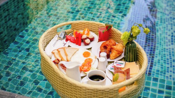 A wicker basket filled with breakfast items on a poolside. - Silkian Hoian Boutique Hotel & Spa (Da Nang)